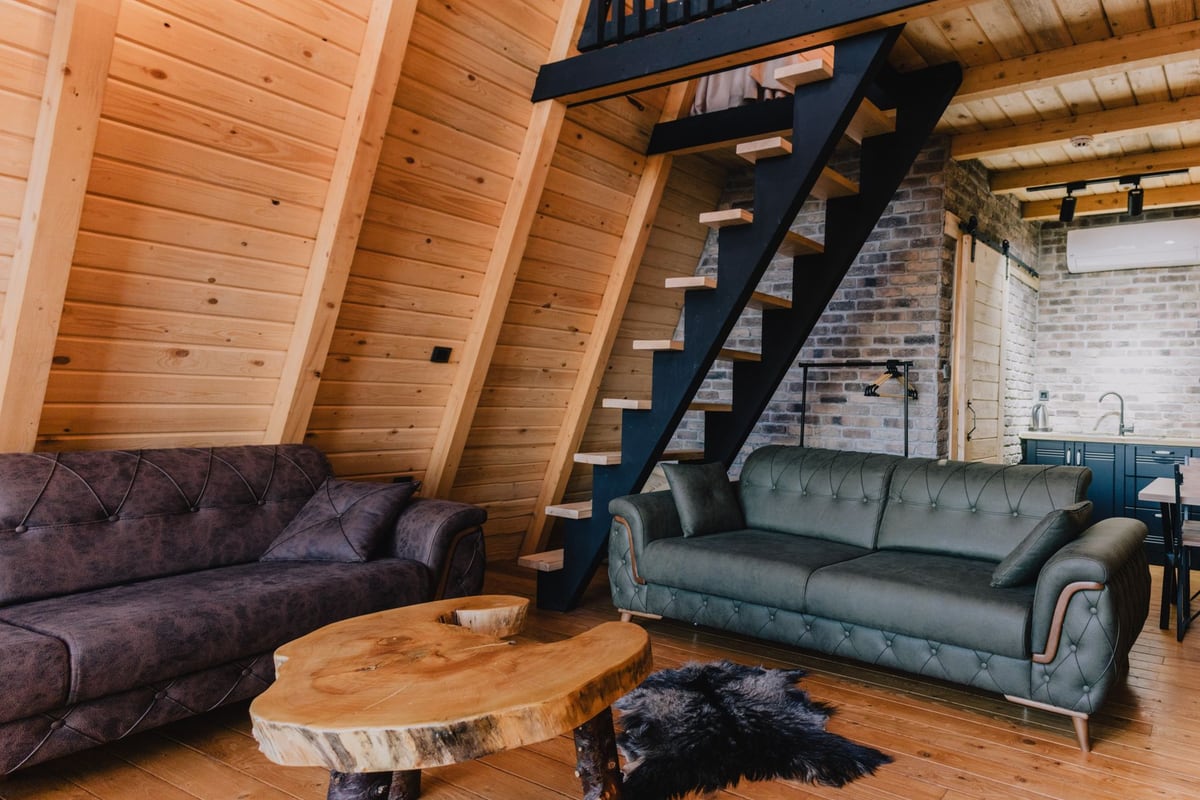 Séjour de chalet en bois avec escalier métallique et éclairage sur rail