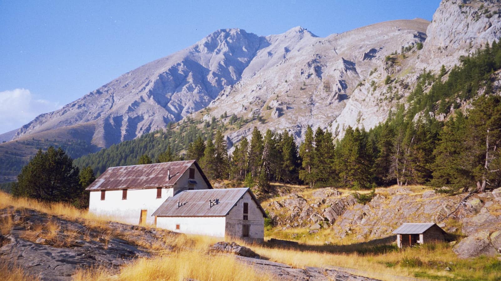 Hameau de montagne sous une crête calcaire, mélèzes et prairie sèche des Alpes du Sud